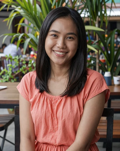 Cambodian woman Sreyka from Phnom Penh in a coral blouse at a tropical cafe