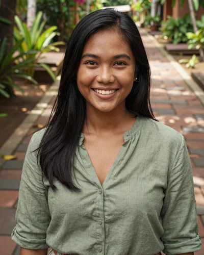 Indonesian woman Sari from Yogyakarta in a sage green blouse near tropical greenery